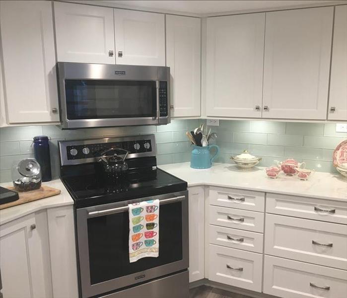 kitchen with white cabinets and teal backsplash with black oven