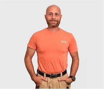 male in black shirt standing in front of gray background