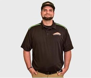 male in black shirt standing in front of gray background