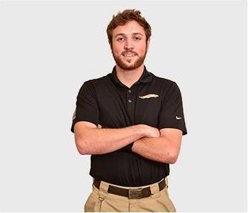 Male in black polo standing in front of light background